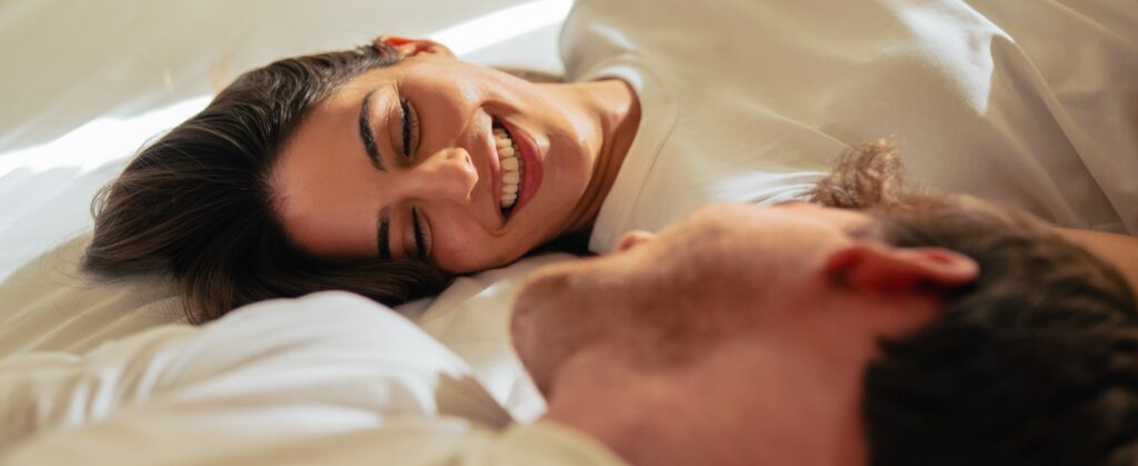 Beautiful happy loving young smiling couple relaxing in bed, looking at each other.