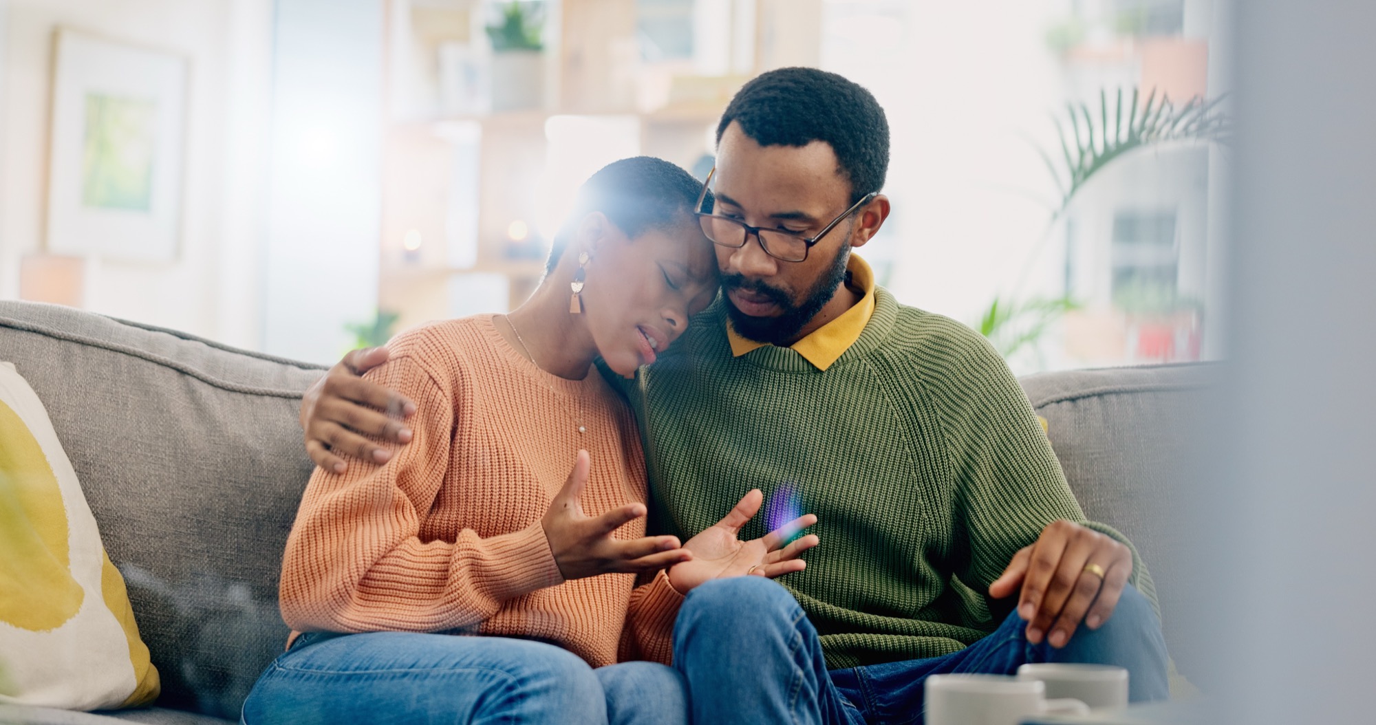 Sad, home and black couple with hug, conversation and emotions with discussion, grief and loss.