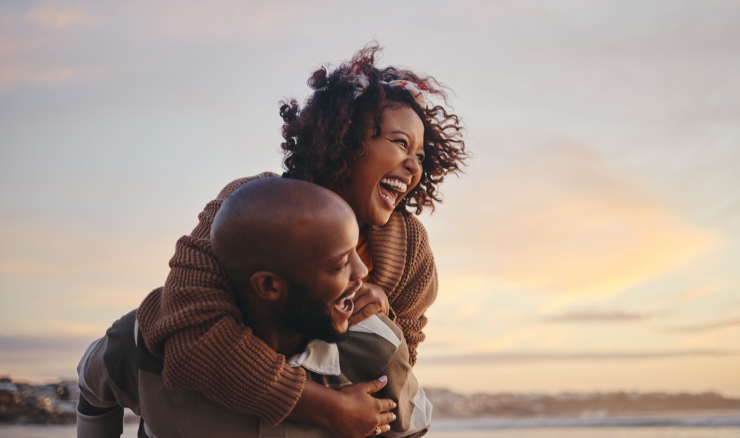 Black couple, travel and beach fun while laughing on sunset nature adventure