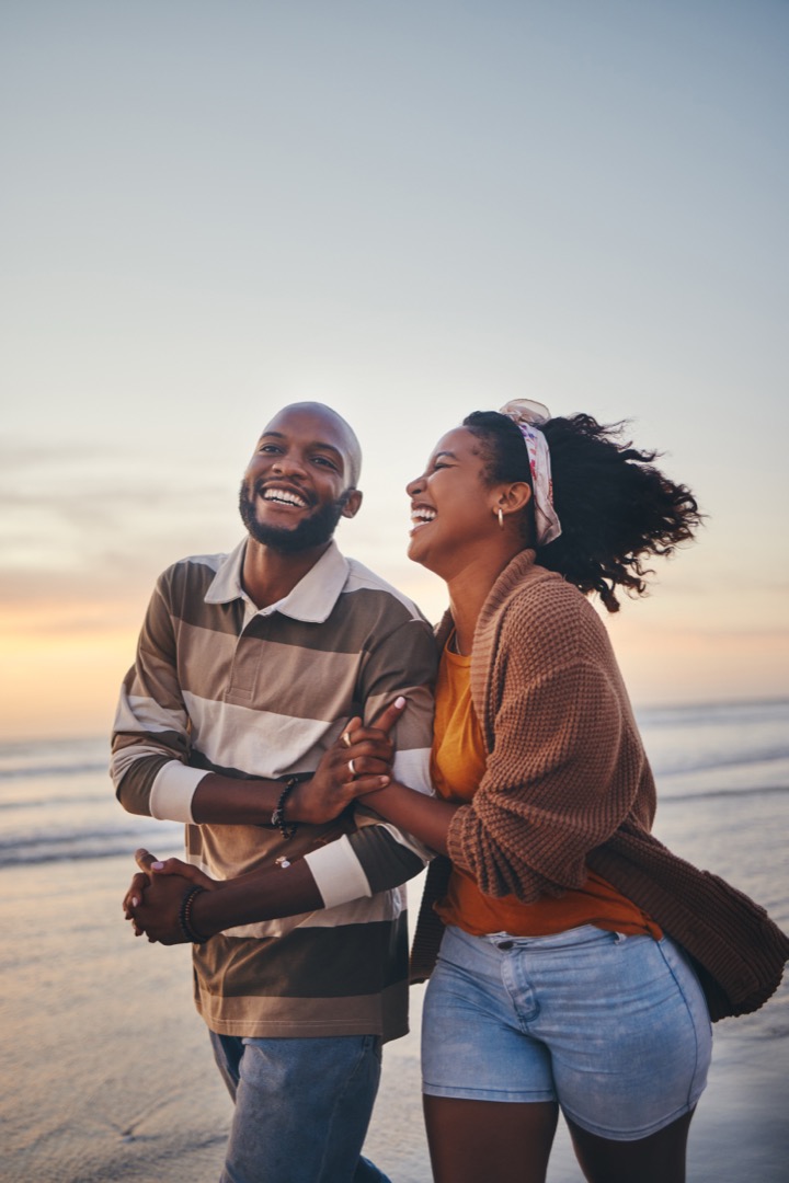 Happy couple, love and travel at the beach holding hands
