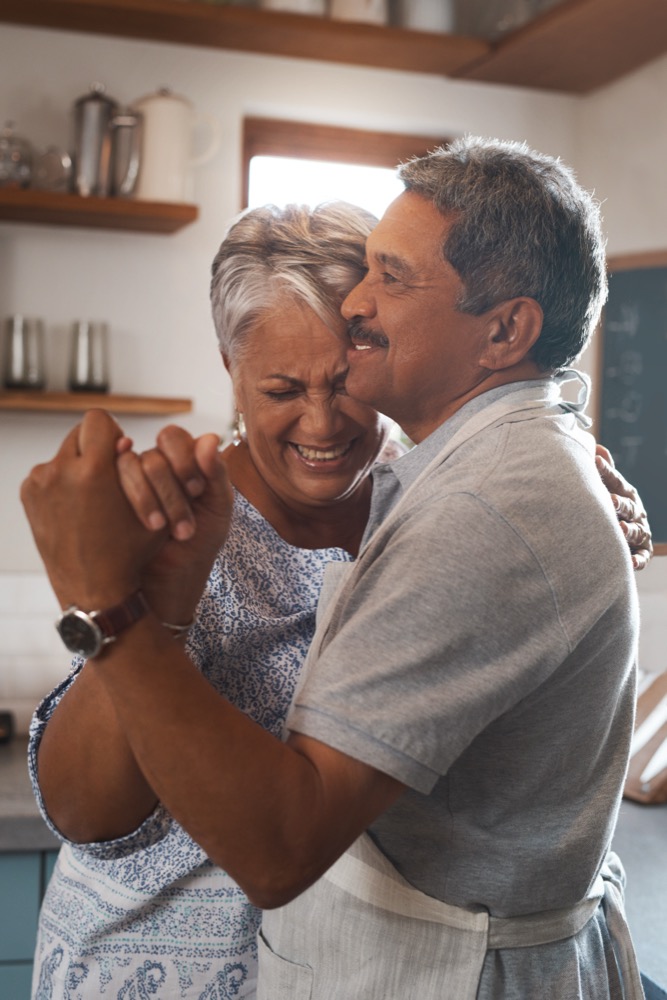 Dance, laugh and senior couple in kitchen for bonding, loving relationship and romance together in home. Retirement, marriage and happy mature man and woman for cooking supper, lunch and dinner.