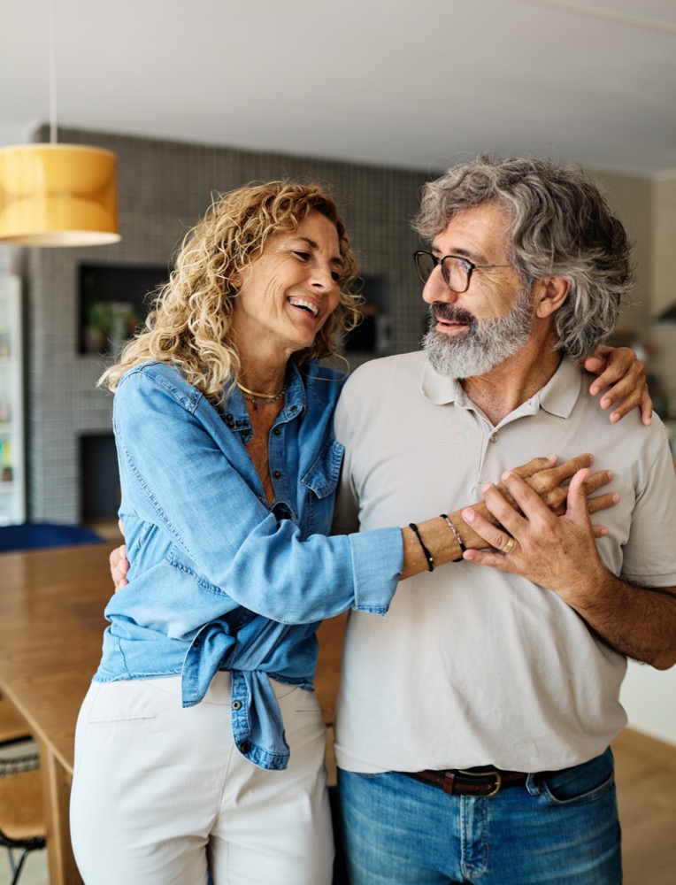 Portrait of a happy senior couple embracing hugging and bonding at home